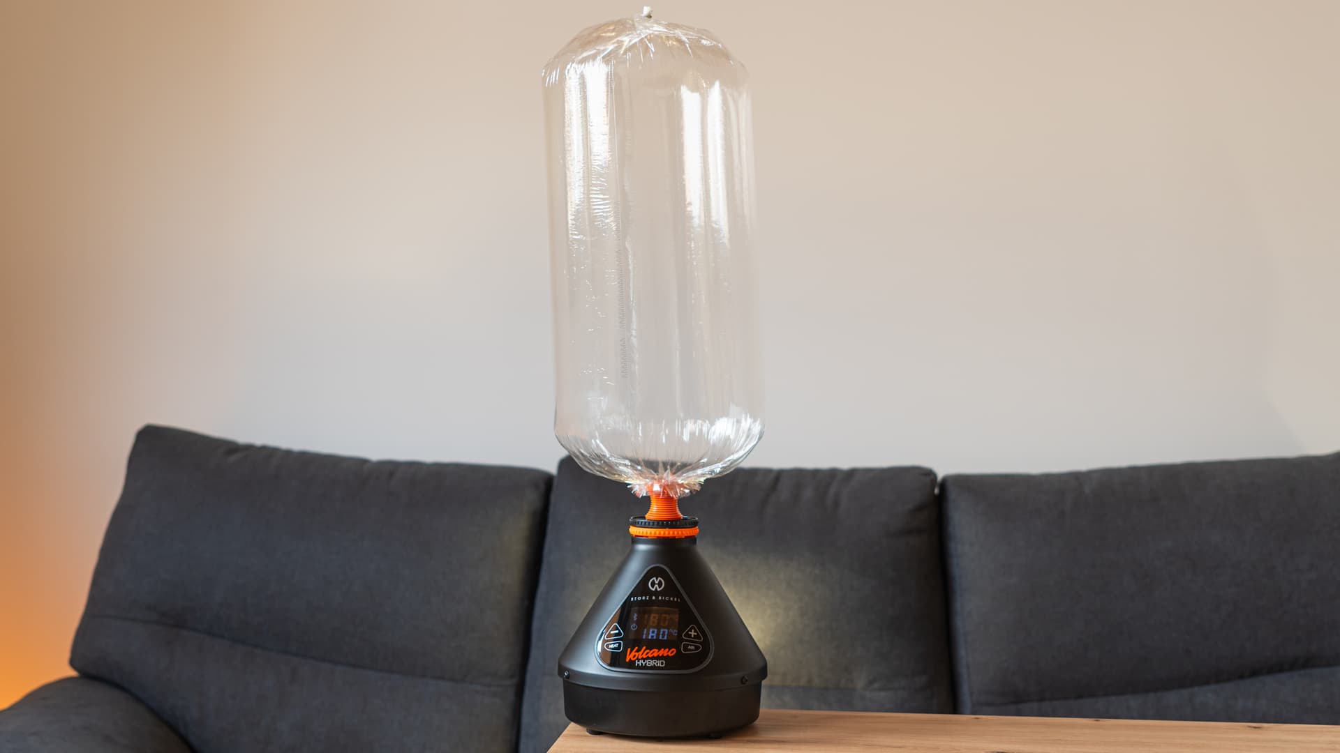 A Volcano Hybrid desktop vaporizer on a wooden table at home with a filled vapor balloon attached