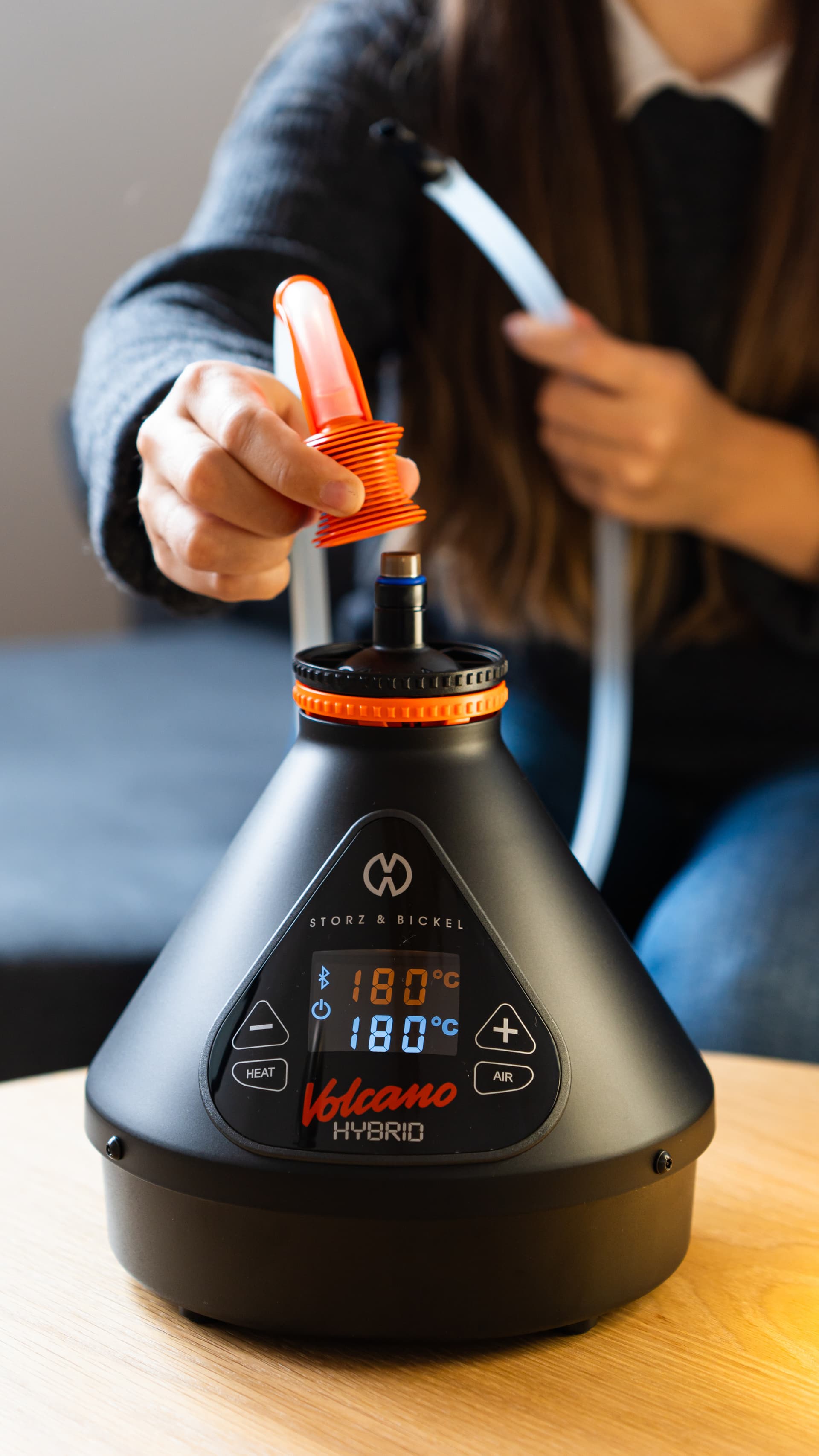 Hand setzt orangefarbenen Schlauch-Ventiladapter auf die Füllkammer des Volcano Hybrid