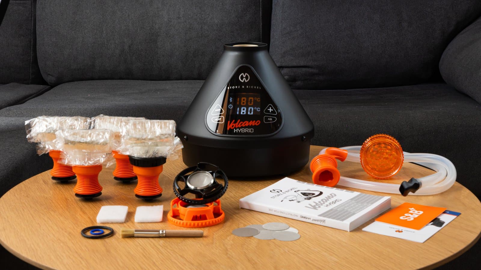 Schwarzer Volcano Hybrid mit komplettem Zubehör-Set auf Holztisch neben Sofa ausgebreitet