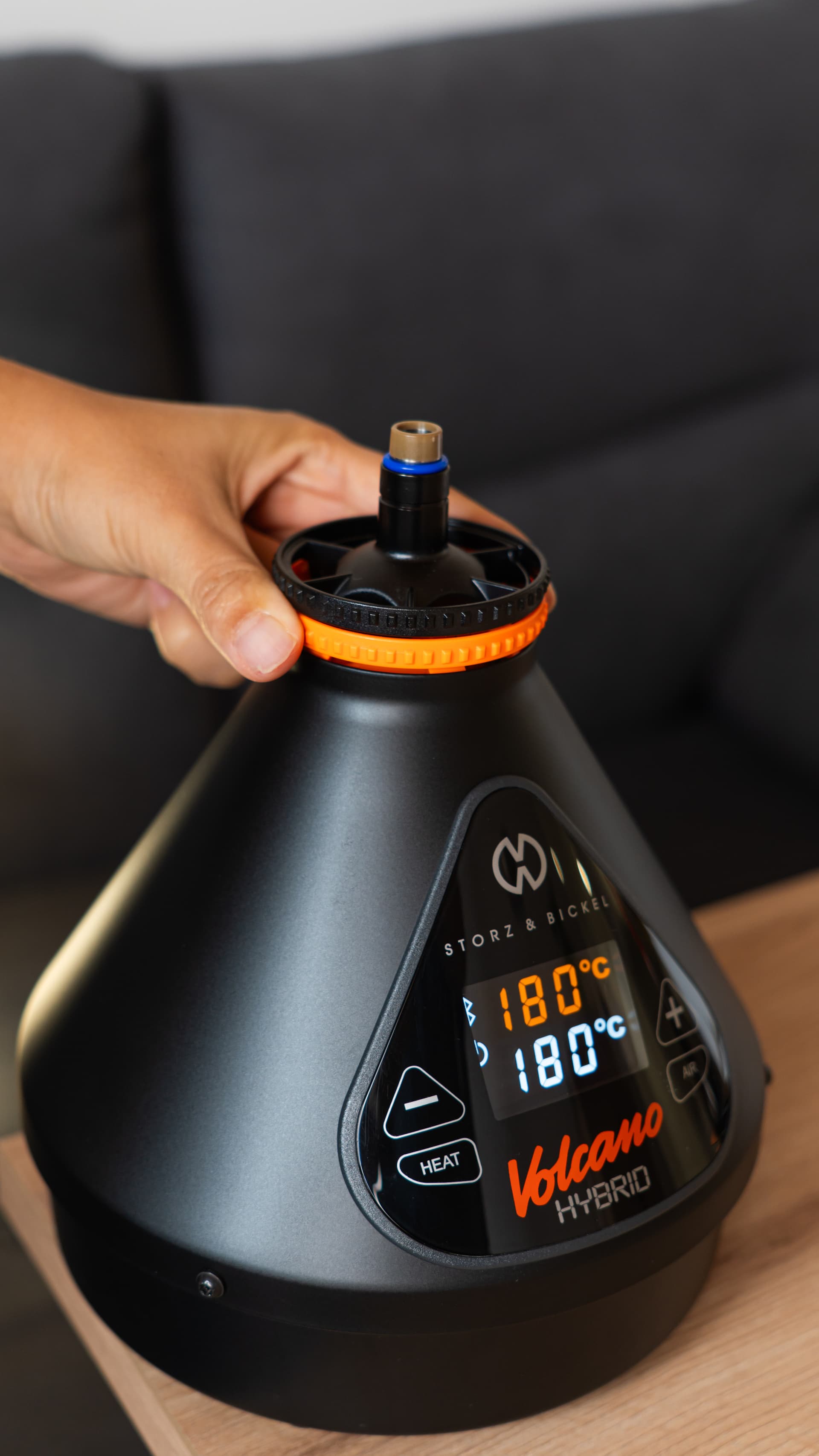 Hand setzt Füllkammer auf den Volcano Hybrid bei 180°C auf Couchtisch