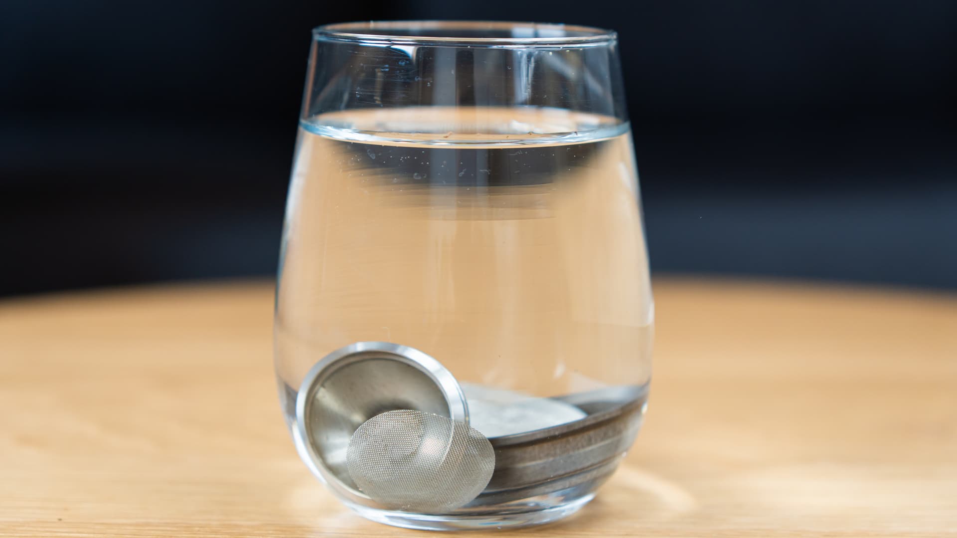 Edelstahlsiebe des Volcano Hybrid in Reinigungslösung in einem Glas auf Holztisch
