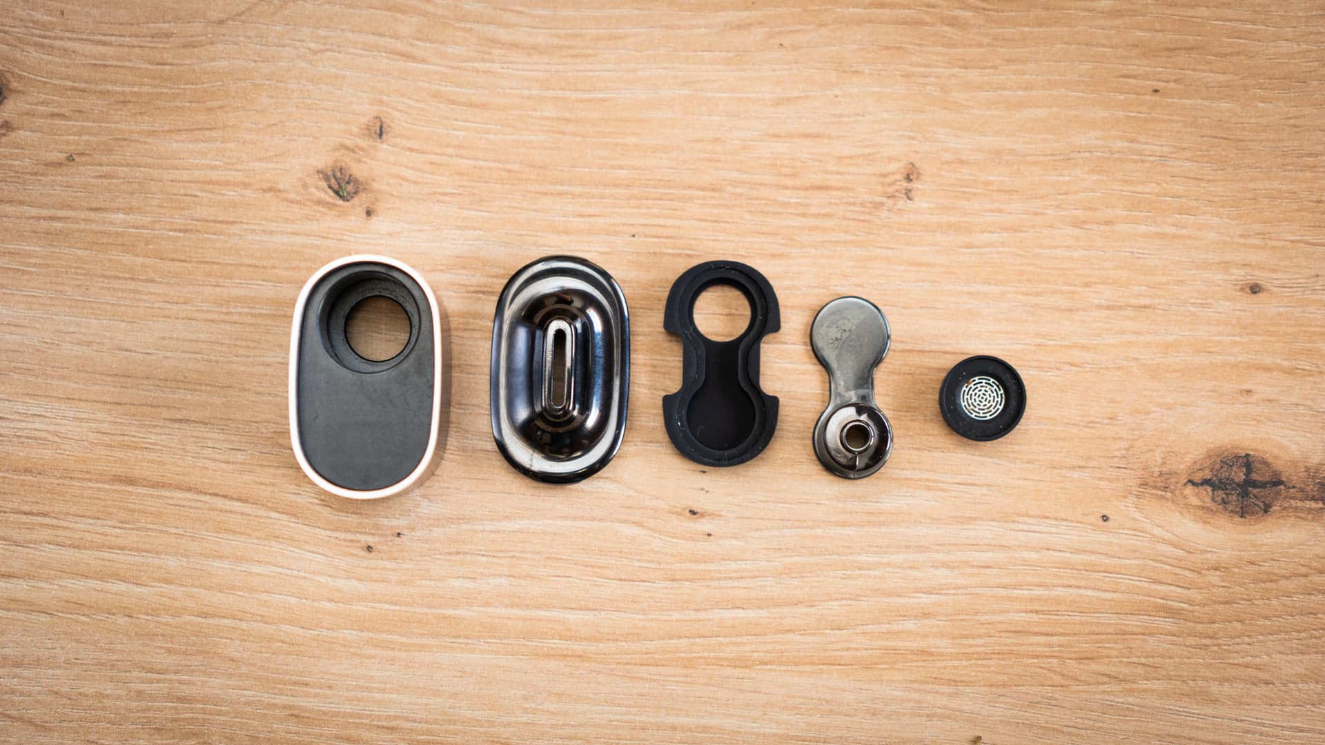 A cooling unit fully disassembled into its mouthpiece, screens, and housing parts, laid out flat on a neutral surface