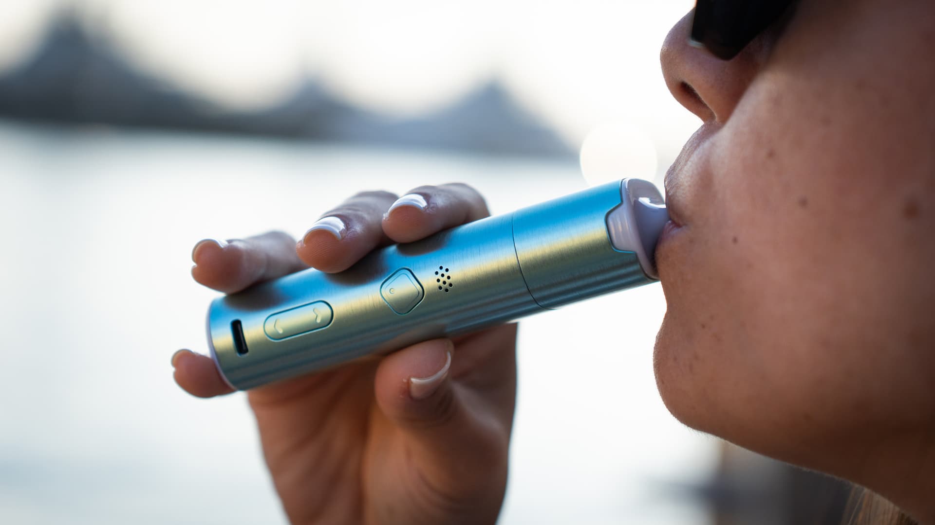 Close-up of a person taking a slow, relaxed draw from a portable vaporizer, mouthpiece at the lips