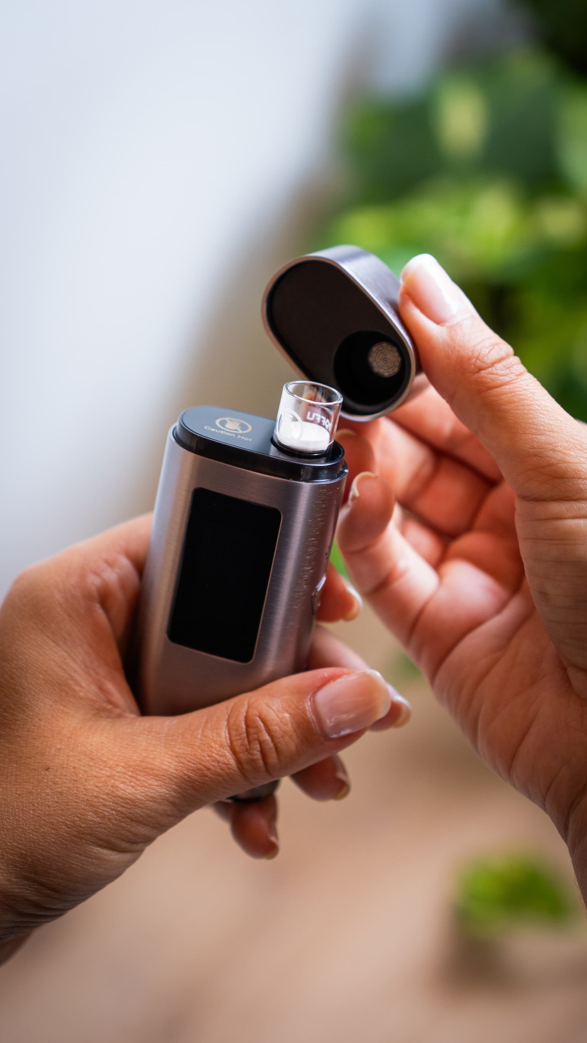 XLUX Roffu with mouthpiece cap open showing exposed ceramic oven and glass chamber against green bokeh background