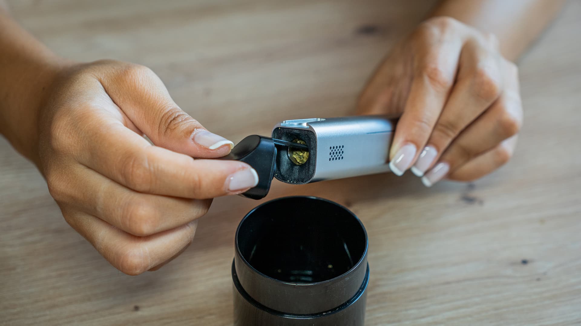 Tipping spent cannabis from a silver XMax V3 Pro into a container