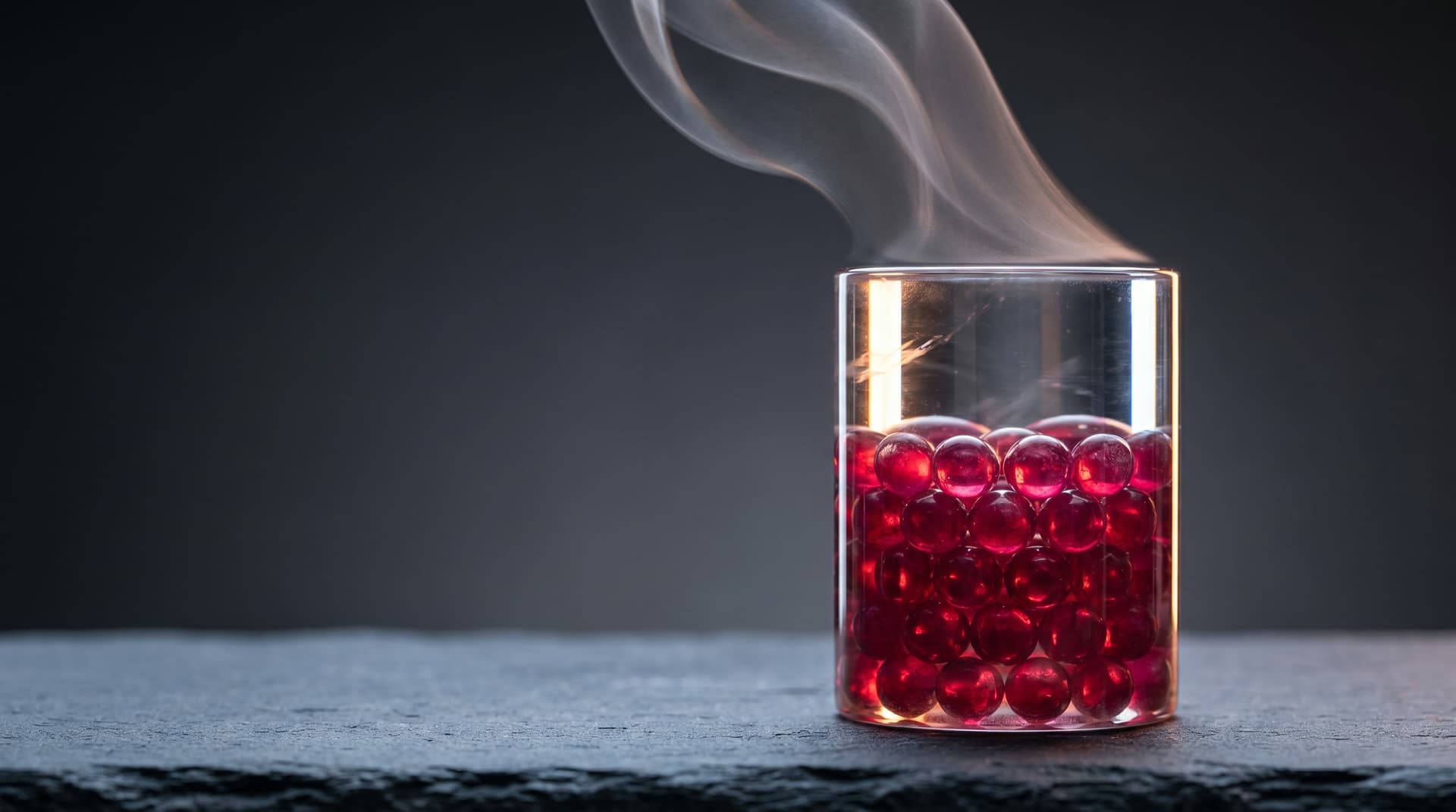 A packed ruby ball chamber with visible thermal shimmer and a faint vapor trail rising from the spheres