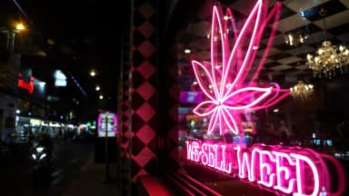 A neon sign reading We Sell Weed glows in the window of a cannabis dispensary at night in Bangkok. | Valeria Mongelli/ZUMAPRESS/Newscom
