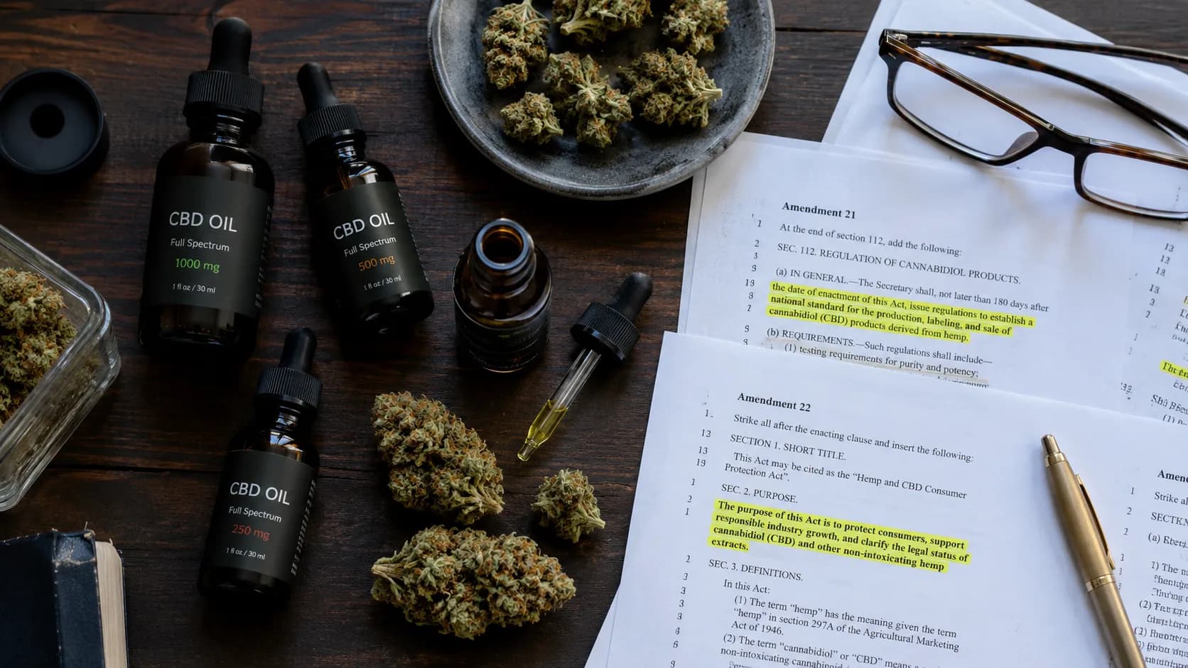 CBD oil bottles and cannabis flower buds arranged on a desk alongside highlighted legislative amendment papers. | Illustration: VapeExperts/AI