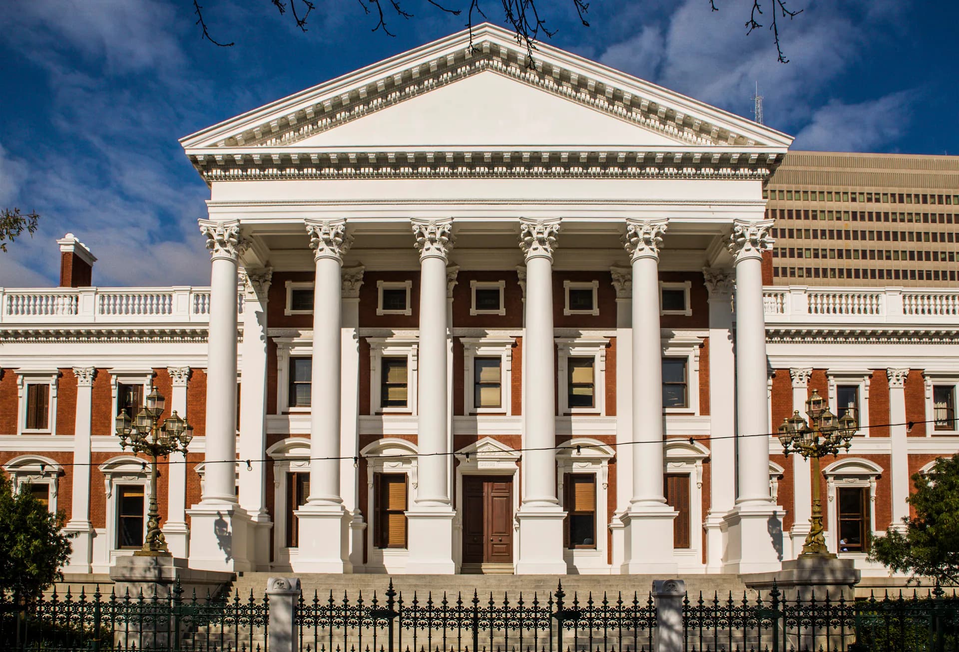 The Corinthian columns of the Houses of Parliament stand against a blue sky in Cape Town, Western Cape, South Africa.