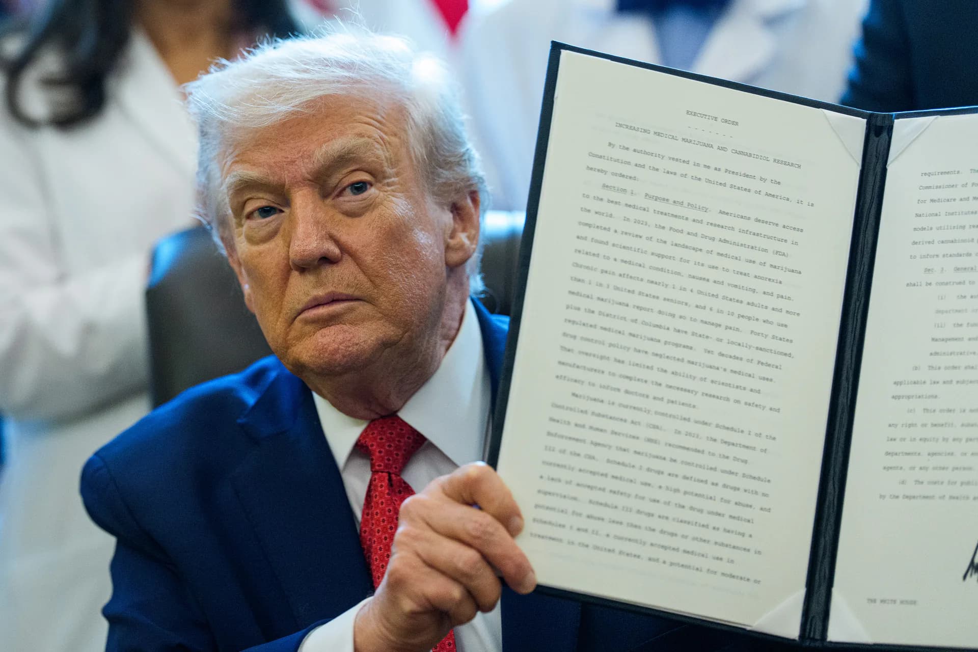 United States President Donald J. Trump displays an executive order to reschedule marijuana from a schedule one to a schedule three controlled substance after signing it in the Oval Office of the White House in Washington, Thursday, Dec. 18, 2025.