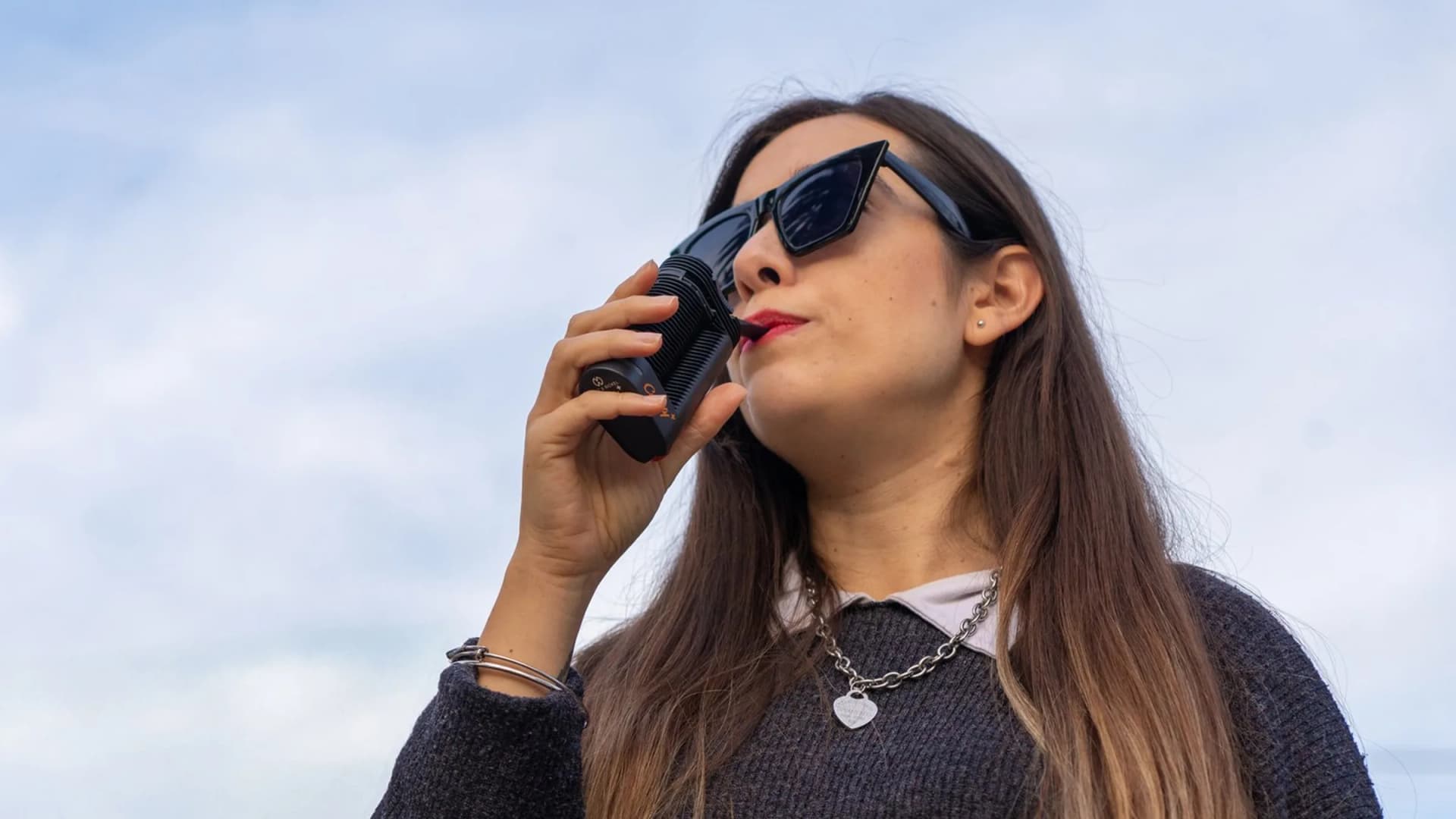 A woman inhales from a Storz & Bickel Crafty+ vaporizer outdoors. Devices like these are now permitted for Georgia medical cannabis patients under SB 220. (VapeExperts)