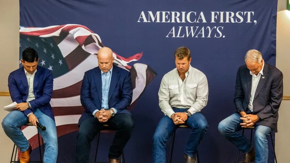 Four men sit on stools with heads bowed in prayer in front of a banner reading America First, Always with an American flag image. | Rep. Ryan Zinke/Wikimedia Commons (Public domain)