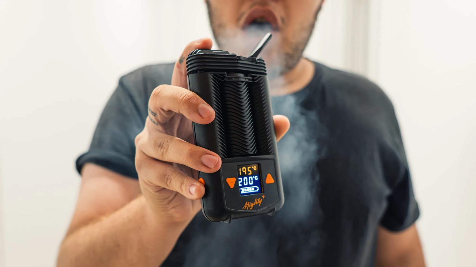A user exhales vapor while holding a Storz & Bickel Mighty+ vaporizer. Large clouds like these can lead dry herb vape users to overestimate how much material they are actually consuming. (VapeExperts)