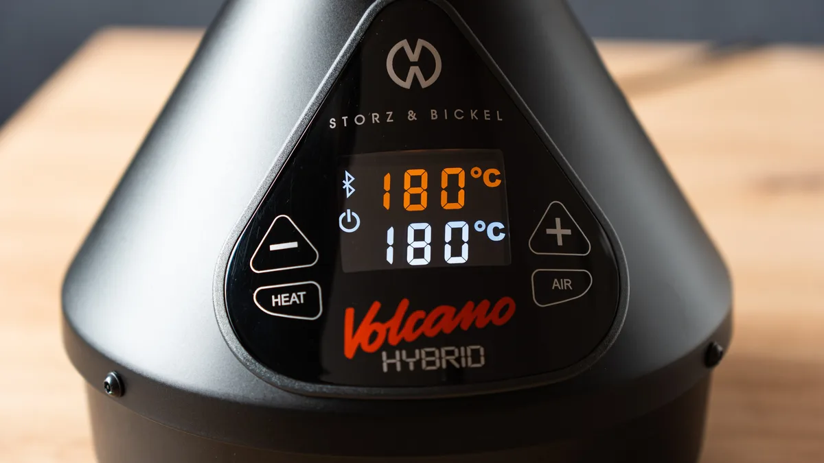 Close-up of a Volcano Hybrid vaporizer's control panel and digital display showing 180 degrees Celsius on a wooden table. | VapeExperts