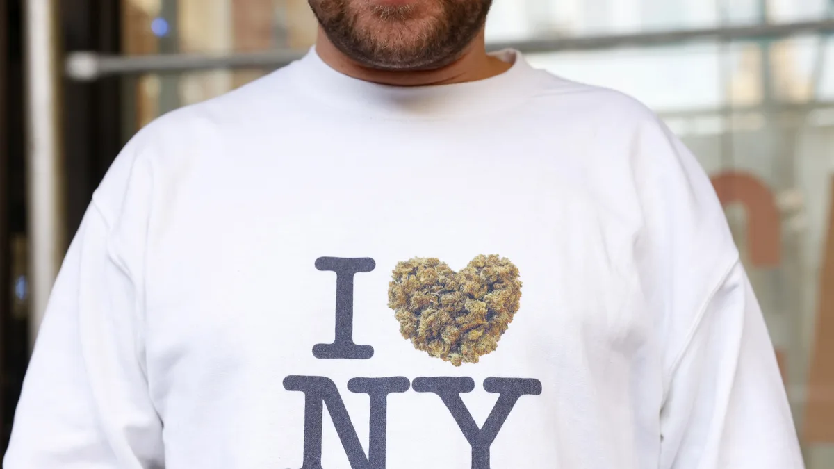 A man wears an I Love NY sweatshirt with a heart made of marijuana outside Housing Works Cannabis Co. in New York City on Dec. 29, 2022. The dispensary opened that day as the city's first legal recreational shop. | John Angelillo/UPI/Newscom