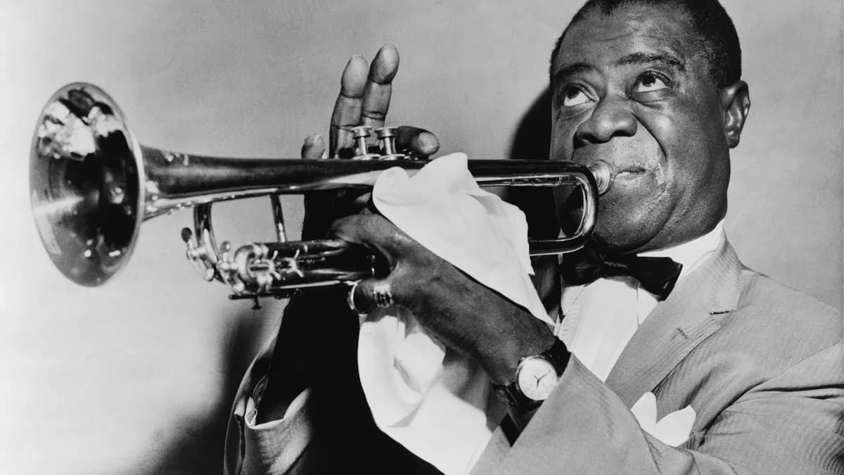 Black and white photo of Louis Armstrong playing a trumpet while holding a white handkerchief. | World-Telegram staff photographer/Wikimedia Commons (Public domain)