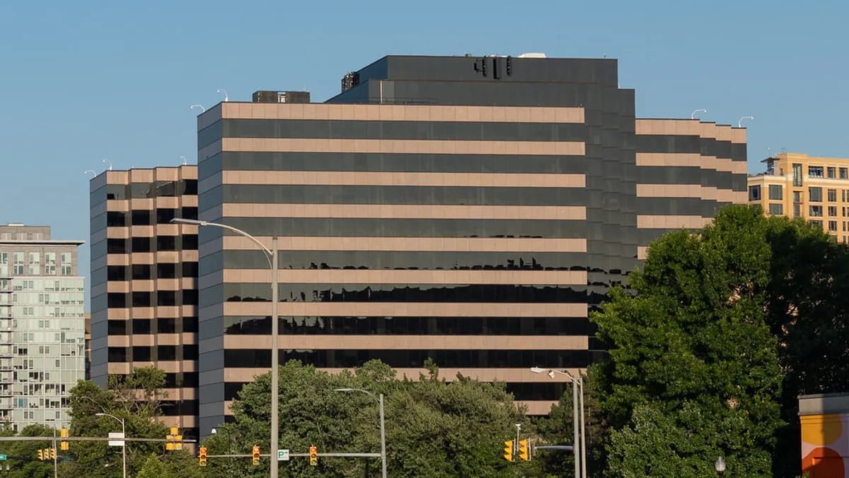 A multi-story glass and stone office building, the DEA headquarters in Arlington, Virginia, seen behind trees and streetlights on a clear day. | Tony Webster/Flickr (CC BY 2.0)
