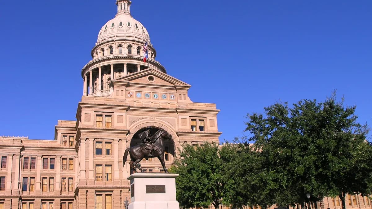 The Texas State Capitol building with its dome, fronted by an equestrian statue and an old cannon on a green lawn under a clear blue sky. | Daniel Mayer/Wikimedia Commons (CC BY-SA 3.0)