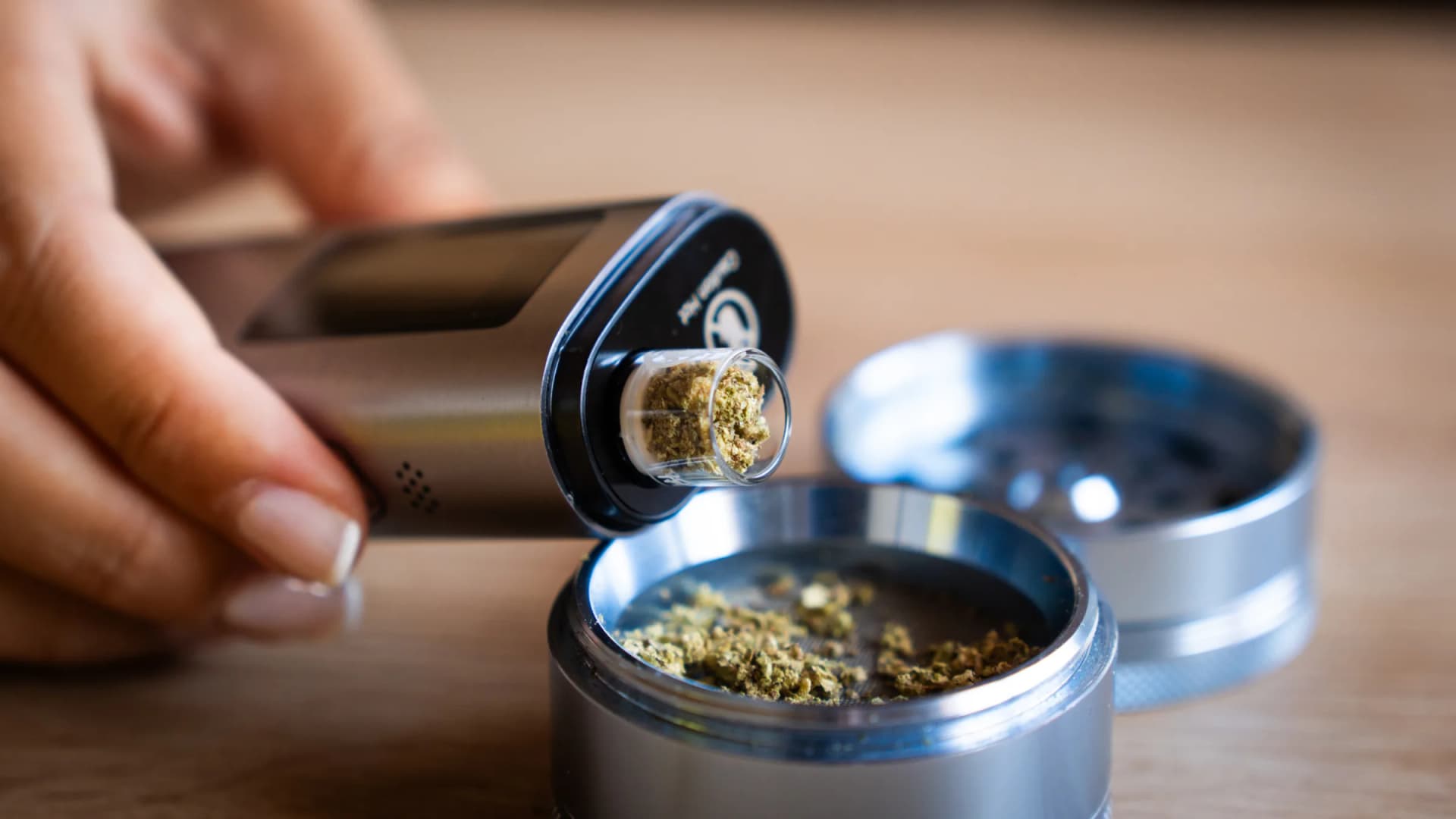 Eine Person füllt gemahlene Cannabisblüten aus einem Grinder in einen XLUX Roffu Vaporizer. Der Eigenanbau und Besitz kleiner Mengen bleibt 2026 für Erwachsene in Deutschland legal. (VapeExperts)