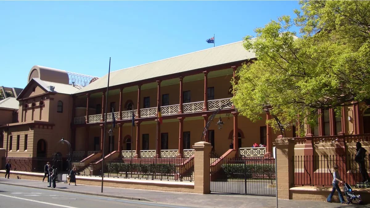 Front facade of the New South Wales Parliament House on Macquarie Street, Sydney, a two-storey sandstone-coloured building with a red-columned... | J Bar at English Wikipedia/Wikimedia Commons (CC BY-SA 3.0)